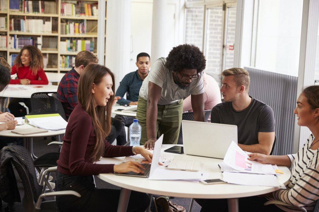 Busy University Library With Students And Tutor