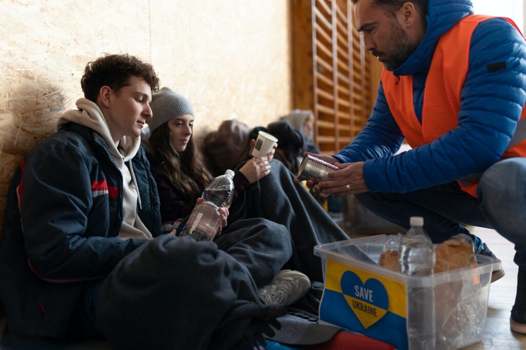 Ukrainian war refugees in temporary shelter and help center getting drinks from volunteers