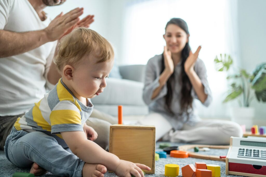 Cha mẹ yêu thương người da trắng nhìn em bé đang chơi trong phòng khách.