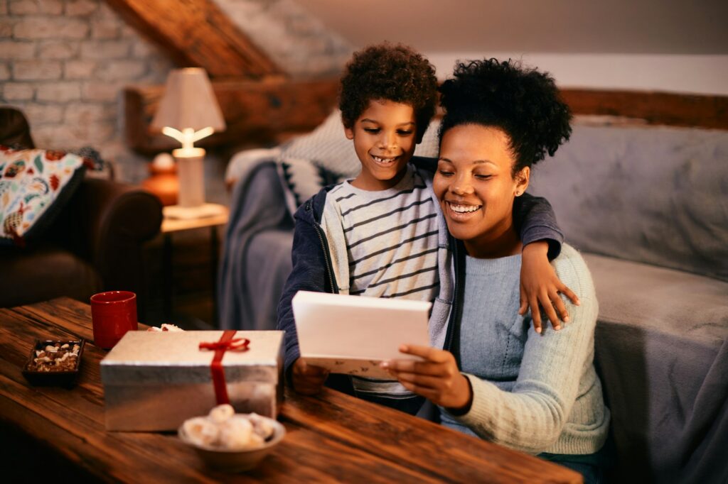 Masayang itim na ina na tumatanggap ng regalo at greeting card mula sa kanyang anak noong Mother's day.