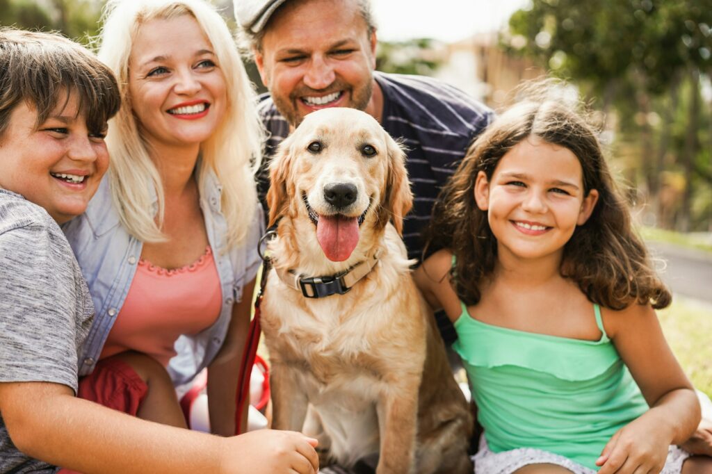 Happy family having fun with children and their dog outdoor summer time - Main focus on dog face