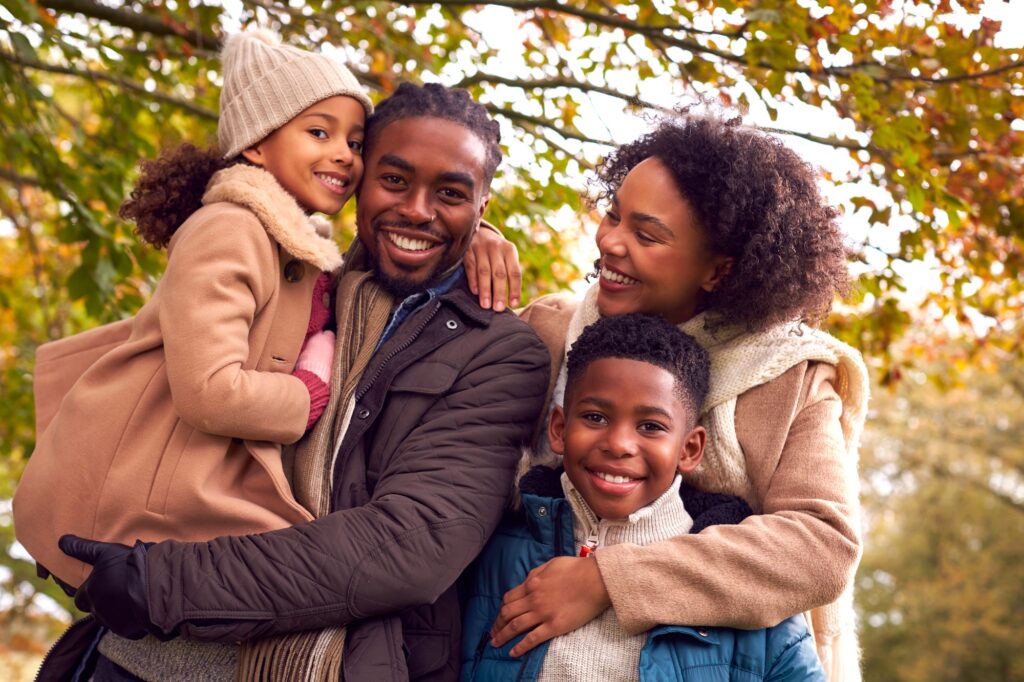 Portrait Of Smiling Family On Walk Through Countryside Against Autumn Trees